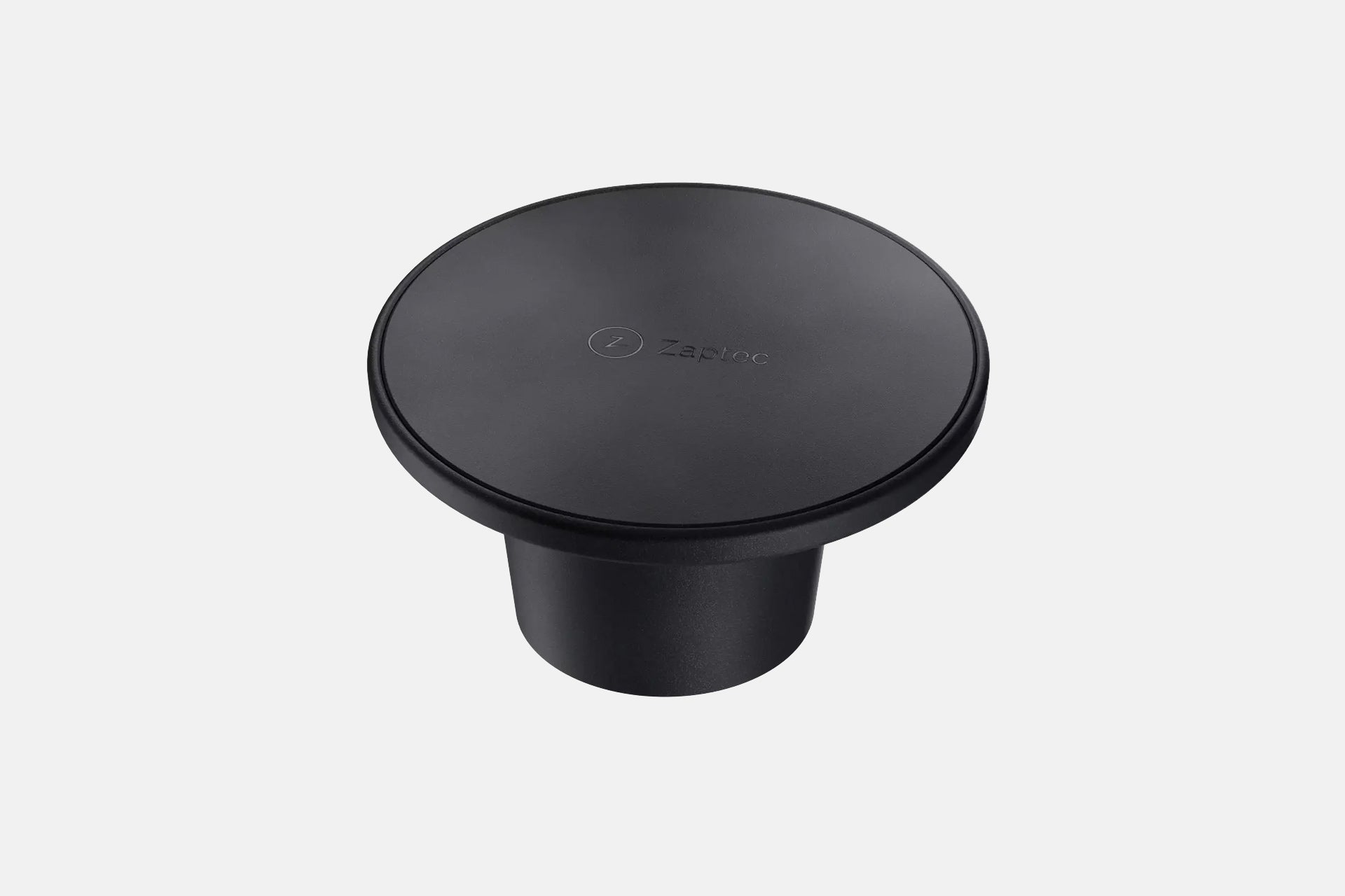 Ein schwarzer, runder Zaptec Chill (Kabelhalterung) mit flacher Oberseite, elegantem Design und Zaptec-Logo, von oben vor einem schlichten hellen Hintergrund betrachtet.